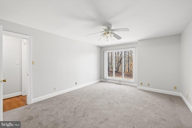 carpeted spare room featuring a ceiling fan and baseboards