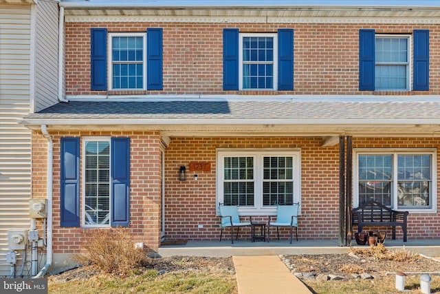 multi unit property featuring a porch and a shingled roof