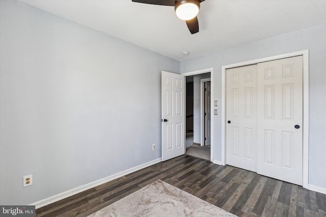 unfurnished bedroom featuring dark wood-style floors, a ceiling fan, baseboards, and a closet