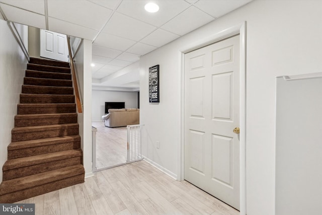 stairway with recessed lighting, wood finished floors, a paneled ceiling, and baseboards