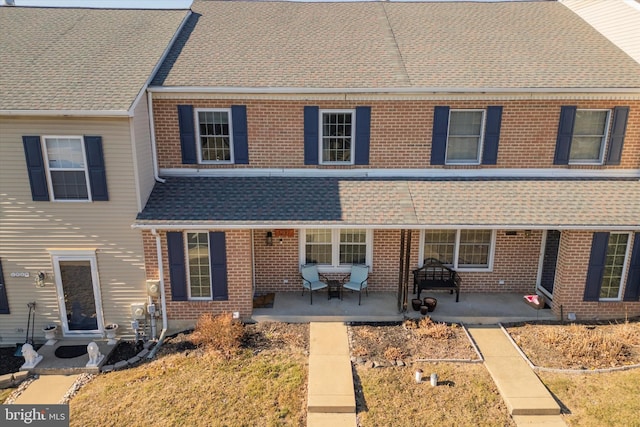 view of property with brick siding and roof with shingles