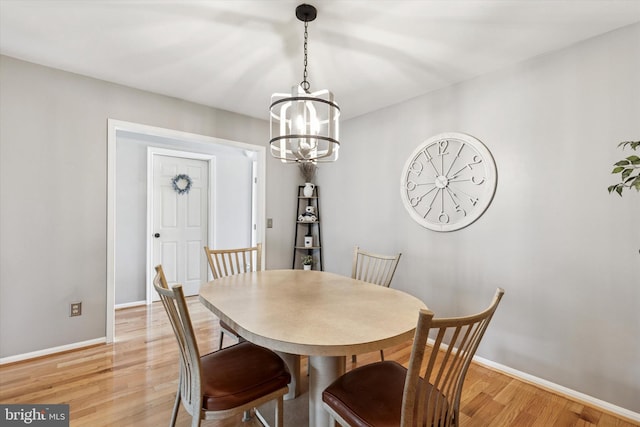 dining space with light wood finished floors, baseboards, and a chandelier