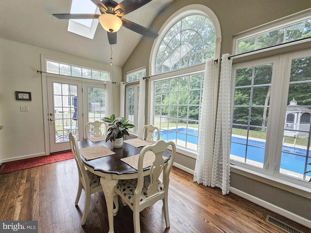 dining area featuring a wealth of natural light, visible vents, lofted ceiling with skylight, and wood finished floors