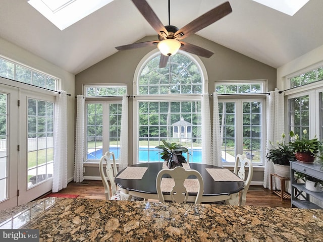 sunroom / solarium featuring vaulted ceiling with skylight, a wealth of natural light, and a ceiling fan