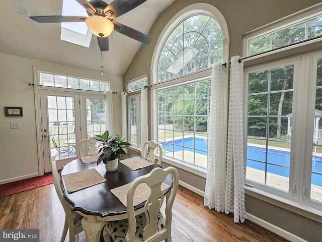 dining space featuring a healthy amount of sunlight, lofted ceiling with skylight, baseboards, and wood finished floors