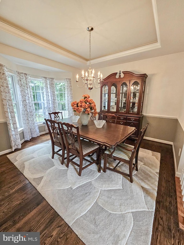 dining area featuring a tray ceiling, crown molding, wood finished floors, a chandelier, and baseboards