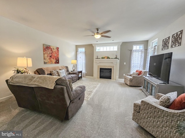 carpeted living room featuring ceiling fan, a fireplace with flush hearth, and baseboards