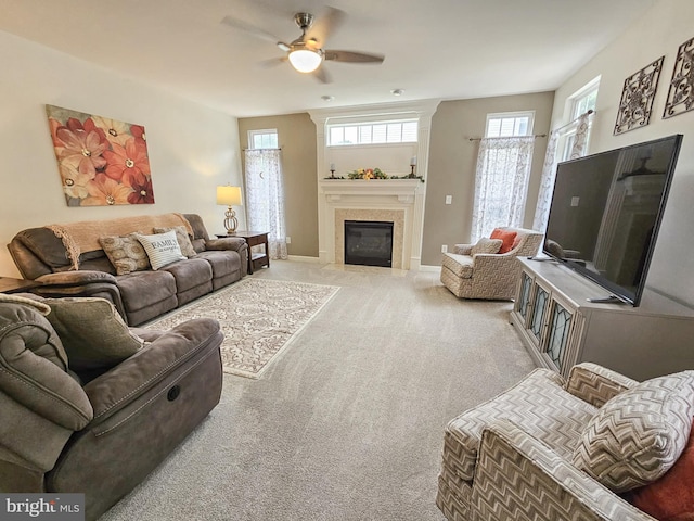 living room with carpet, baseboards, ceiling fan, and a fireplace with flush hearth