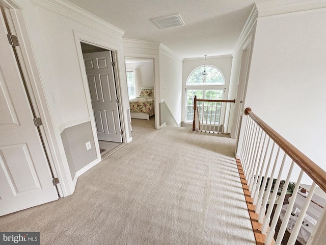 corridor featuring visible vents, baseboards, an upstairs landing, carpet, and crown molding