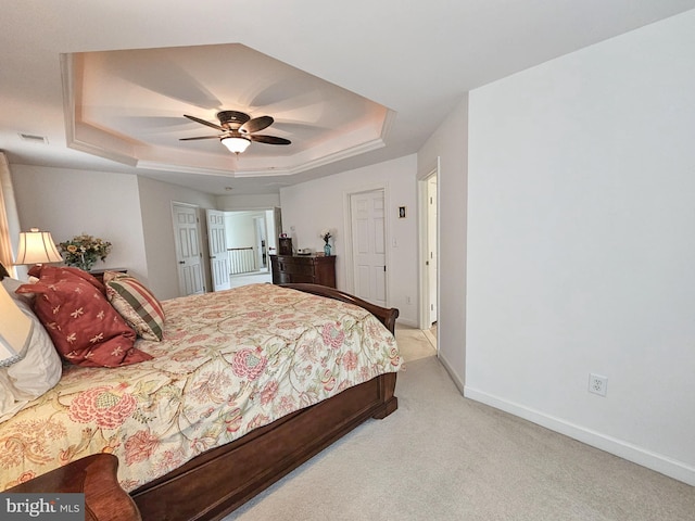 bedroom featuring a tray ceiling, carpet, visible vents, ceiling fan, and baseboards