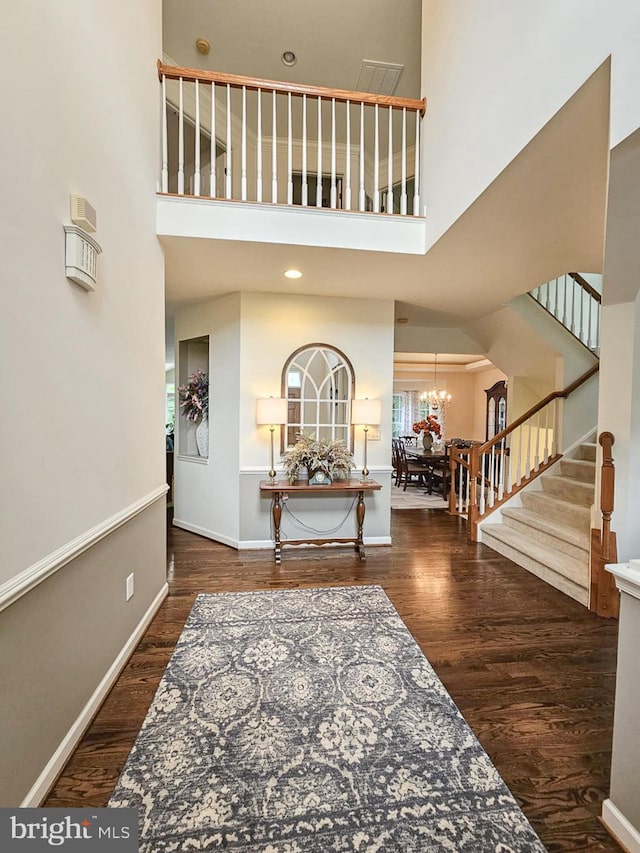 foyer featuring stairs, a high ceiling, wood finished floors, and an inviting chandelier