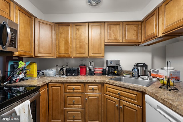 kitchen featuring appliances with stainless steel finishes, brown cabinetry, a sink, and light countertops