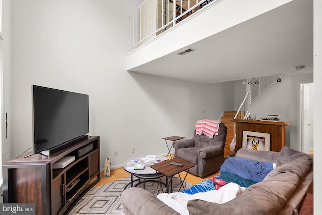 living room featuring stairs, wood finished floors, baseboards, and a high ceiling