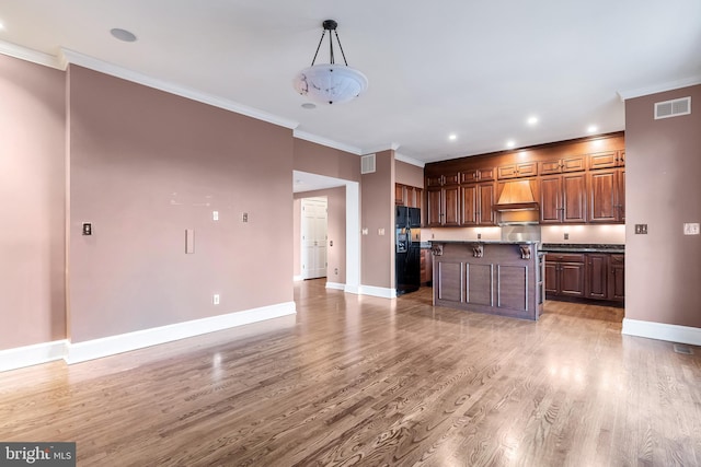 kitchen with light wood finished floors, visible vents, premium range hood, and ornamental molding