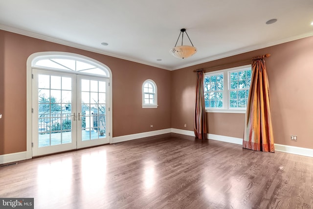 empty room featuring crown molding, wood finished floors, baseboards, and french doors