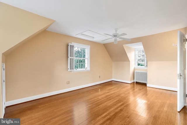 additional living space featuring baseboards, a ceiling fan, wood finished floors, and radiator heating unit