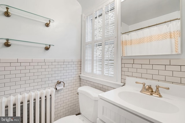 bathroom with vanity, radiator heating unit, curtained shower, tile walls, and toilet