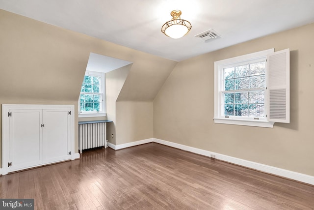 bonus room featuring radiator, wood finished floors, visible vents, baseboards, and vaulted ceiling