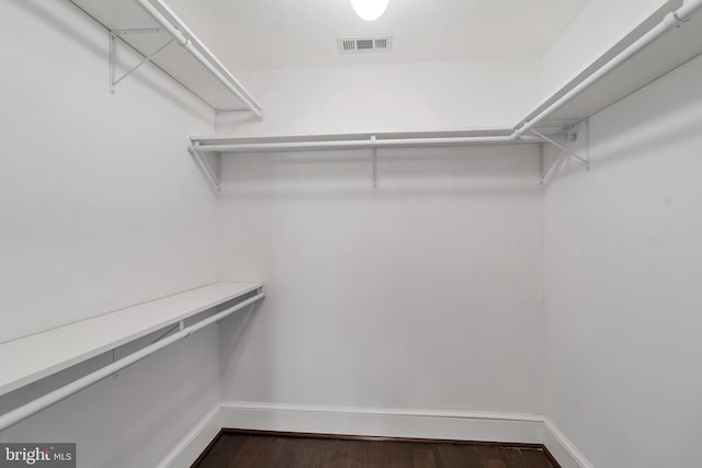 walk in closet with dark wood finished floors and visible vents