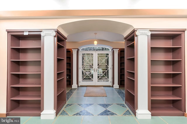 spacious closet with arched walkways, french doors, ornate columns, and vaulted ceiling