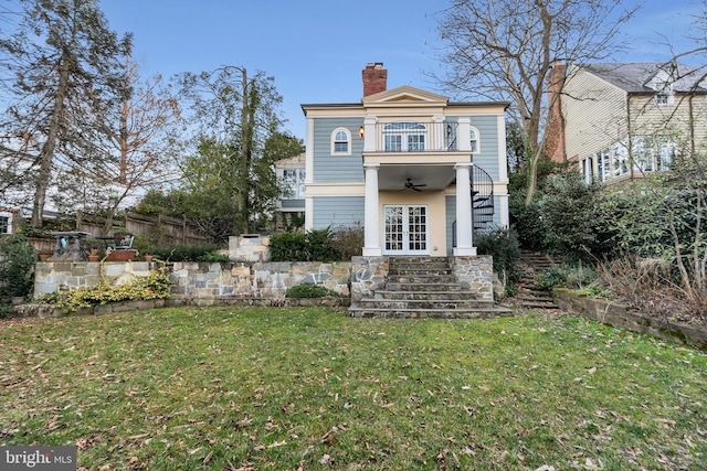 back of house with stairway, a lawn, french doors, a chimney, and a balcony