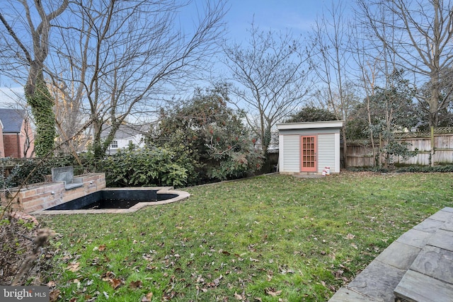 view of yard featuring an outbuilding, a fenced backyard, and a shed