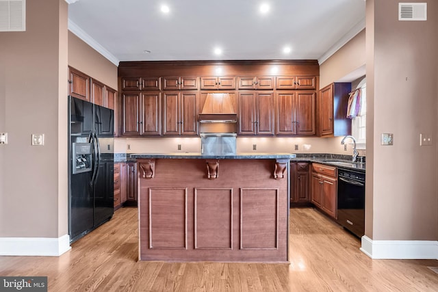 kitchen with black appliances, ornamental molding, visible vents, and a sink