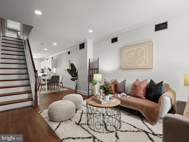 living area featuring visible vents, hardwood / wood-style floors, stairs, and ornamental molding