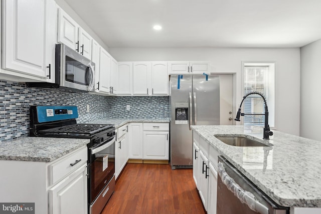 kitchen with appliances with stainless steel finishes, a sink, dark wood finished floors, and white cabinets