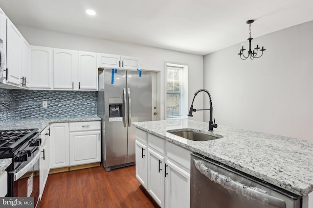 kitchen with tasteful backsplash, white cabinets, appliances with stainless steel finishes, dark wood-style flooring, and a sink