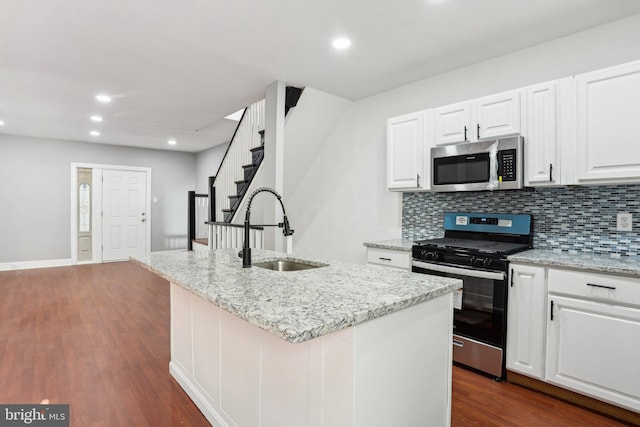 kitchen featuring stainless steel appliances, tasteful backsplash, dark wood-type flooring, white cabinetry, and a sink