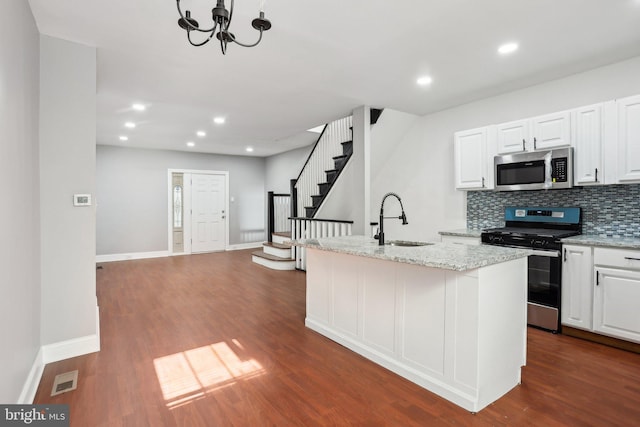 kitchen featuring tasteful backsplash, white cabinets, dark wood-type flooring, stainless steel appliances, and a sink