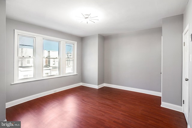 empty room featuring dark wood-type flooring and baseboards