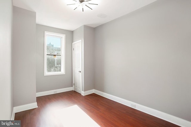 unfurnished room with dark wood-style flooring and baseboards