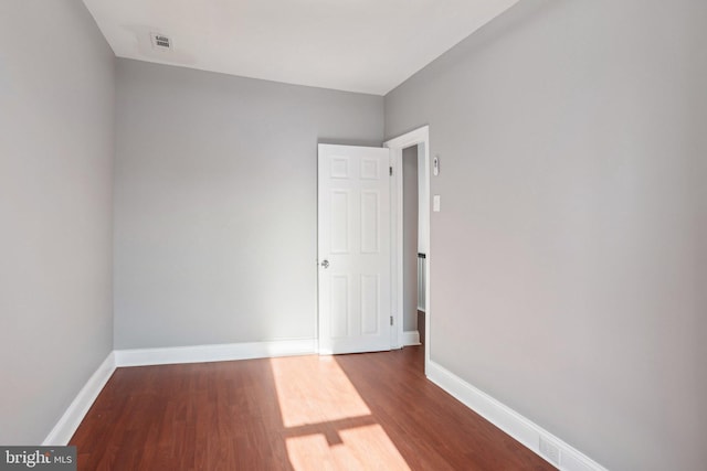 spare room with baseboards, visible vents, and dark wood-style flooring