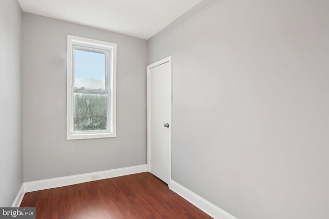 empty room featuring dark wood-style floors and baseboards