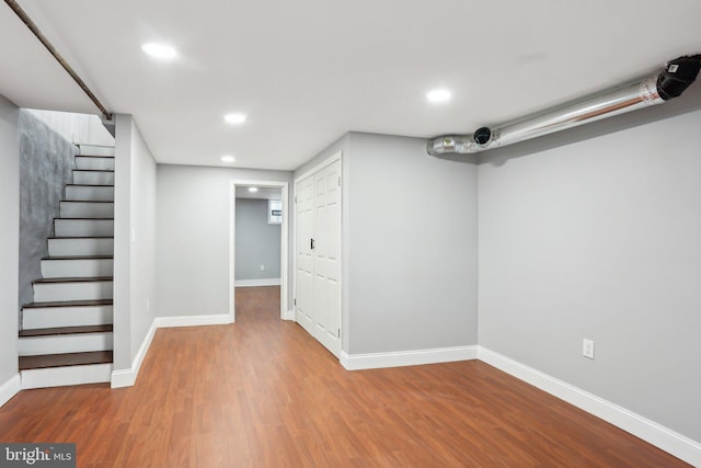 finished below grade area with recessed lighting, stairway, baseboards, and wood finished floors