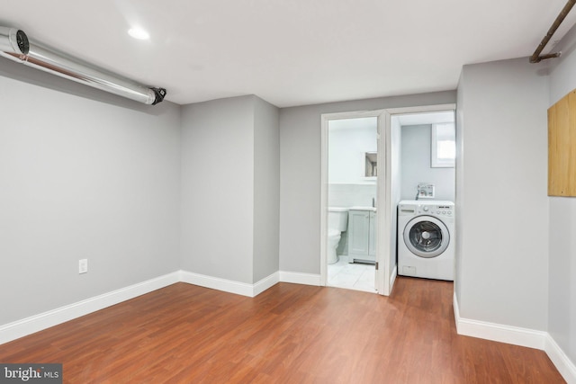 washroom featuring laundry area, washer / clothes dryer, wood finished floors, and baseboards