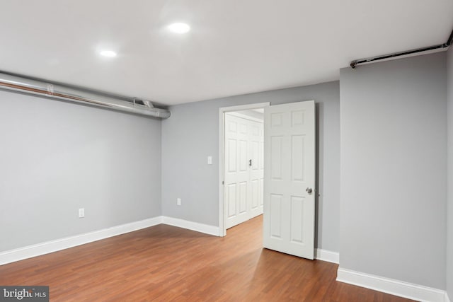 finished below grade area featuring recessed lighting, baseboards, and wood finished floors