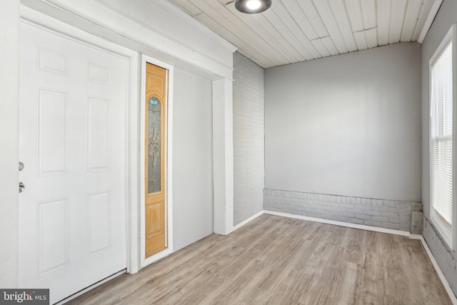 unfurnished room with wood ceiling, brick wall, and light wood finished floors