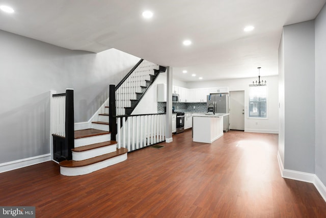 interior space featuring dark wood-style floors, stairway, visible vents, and baseboards