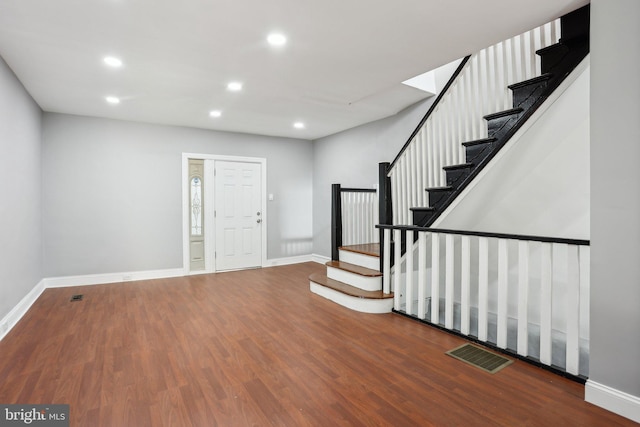 foyer entrance featuring baseboards, stairs, visible vents, and wood finished floors