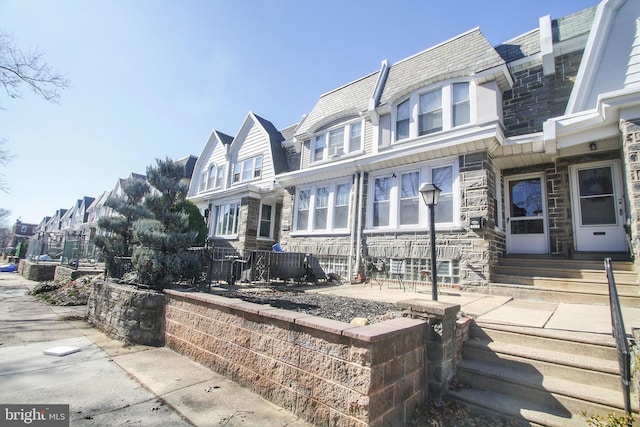 view of front of house with entry steps, stone siding, and a residential view