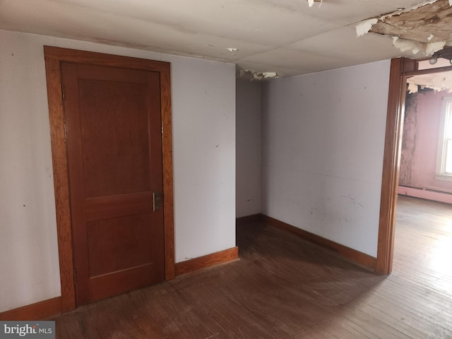 spare room with wood-type flooring, baseboards, and baseboard heating