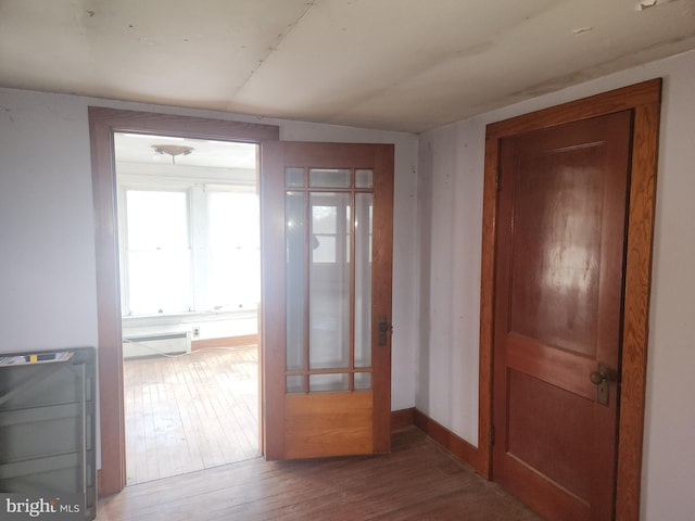 hallway featuring baseboard heating, wood finished floors, and baseboards