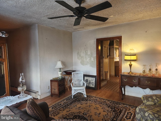 sitting room with baseboards, a ceiling fan, wood finished floors, baseboard heating, and a textured ceiling