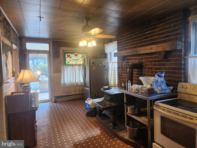 kitchen with a baseboard heating unit, brick wall, electric range, freestanding refrigerator, and carpet