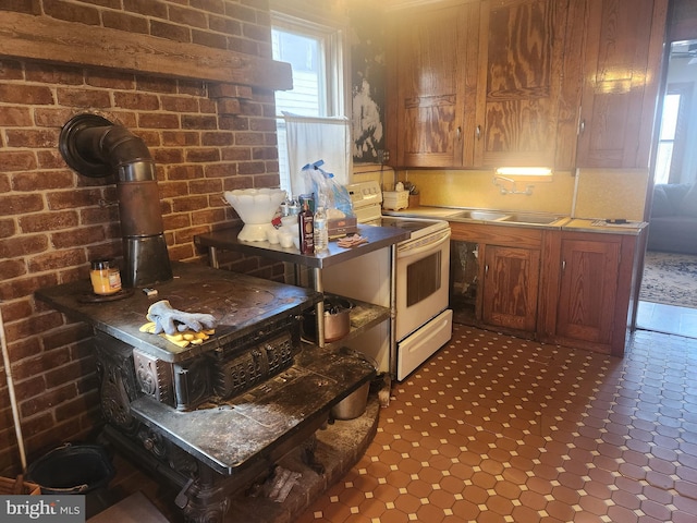 kitchen featuring a wood stove, brick wall, electric range, and a sink