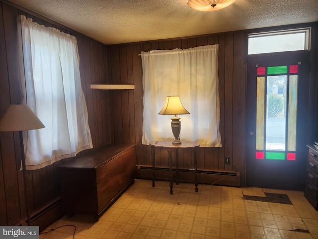 entrance foyer with light floors, a baseboard radiator, wooden walls, and a textured ceiling