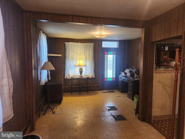 entrance foyer with light floors, wood walls, and baseboard heating